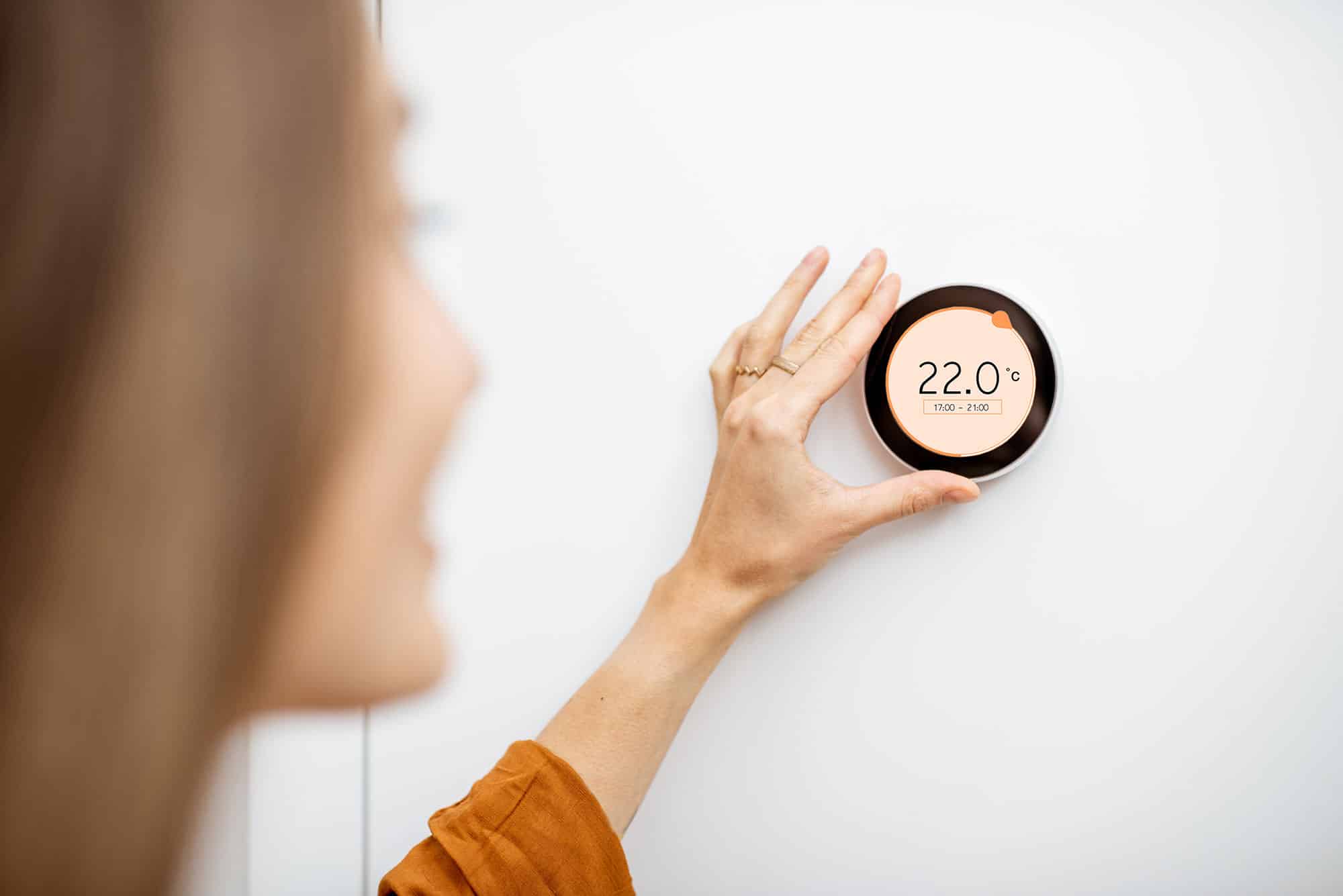 Femme règle le chauffage avec un thermostat digital